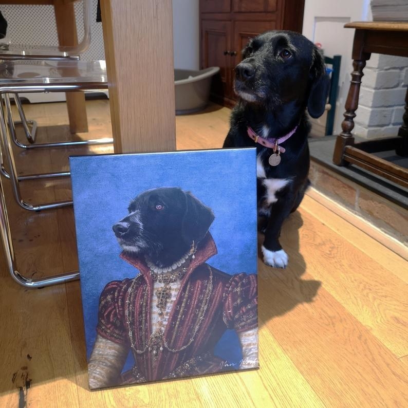 Black and white dog sitting next to its Renaissance portrait