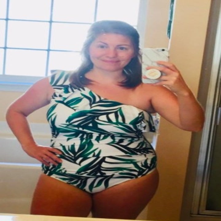 person wearing a tropical printed white one piece swimsuit while posing in the bathroom