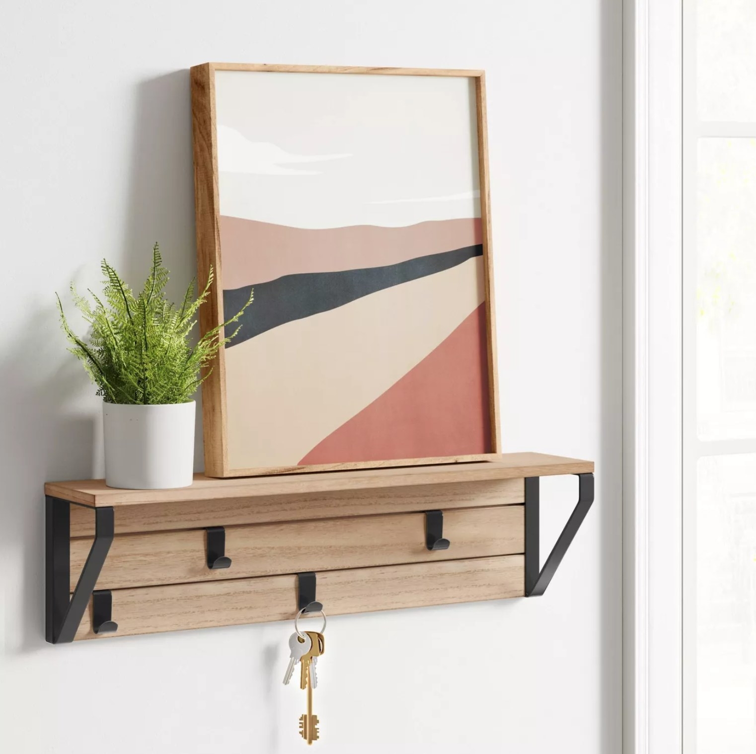 The shelf holding keys, a plant, and a framed picture