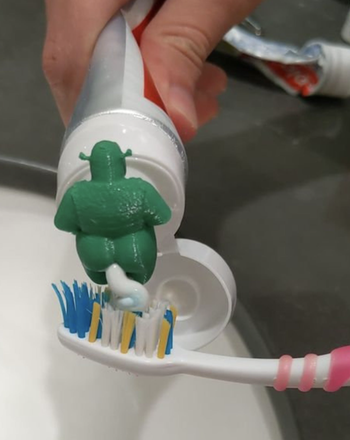 a still image of the 3d printed green ogre with toothpaste coming out of its butt