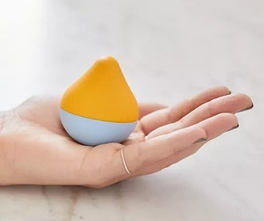 Teardrop shaped toy that fits in the palm of the model's hand 