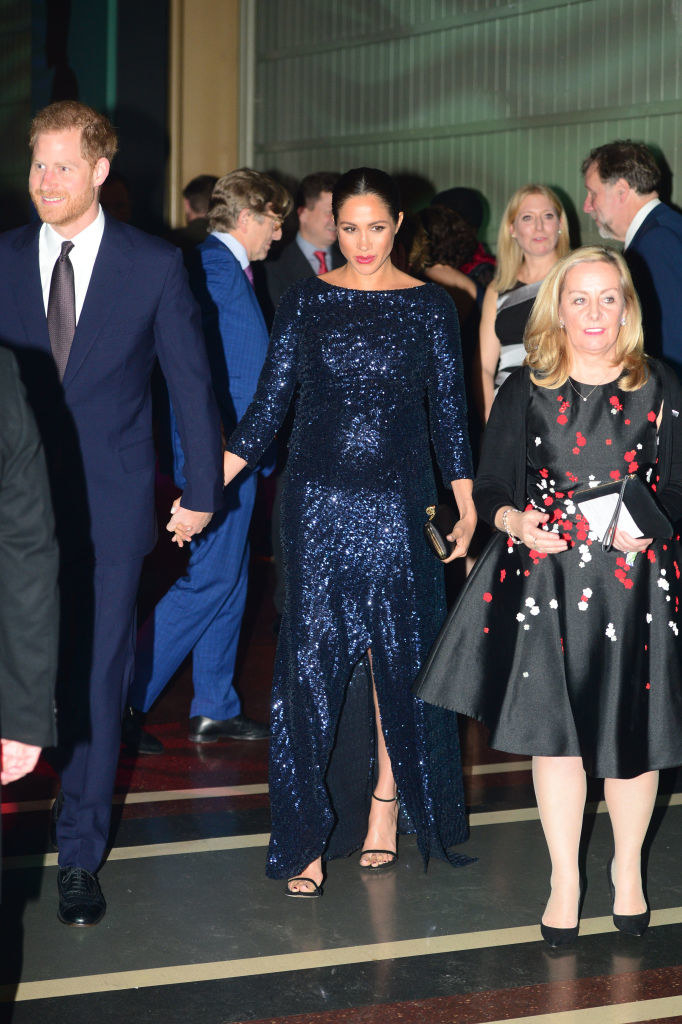 Harry and Meghan, who&#x27;s wear a sequined gown, holding hands as they walk through the event