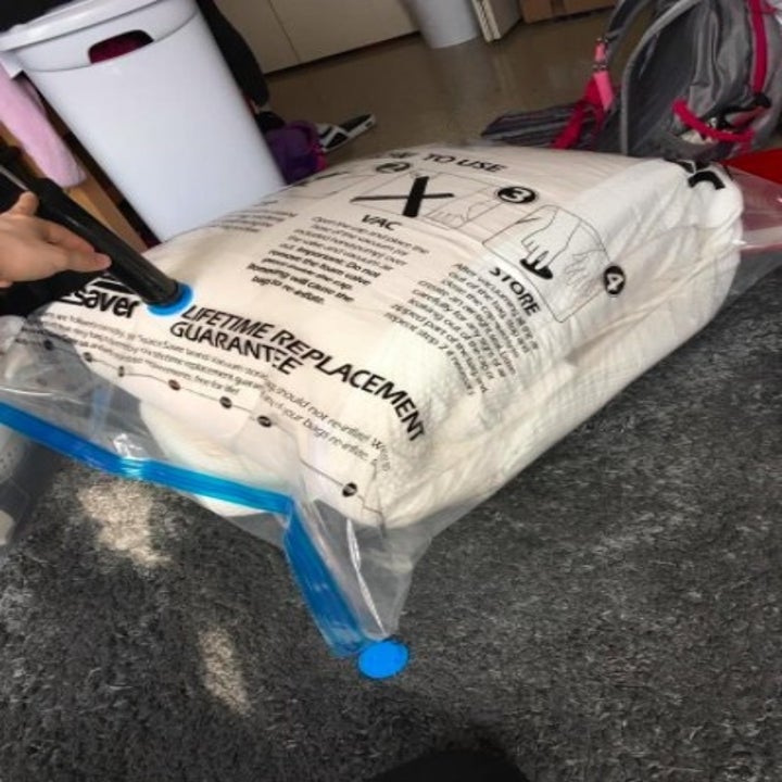 white bedding in a space saver bag with someone sucking the air out of it with a vacuum