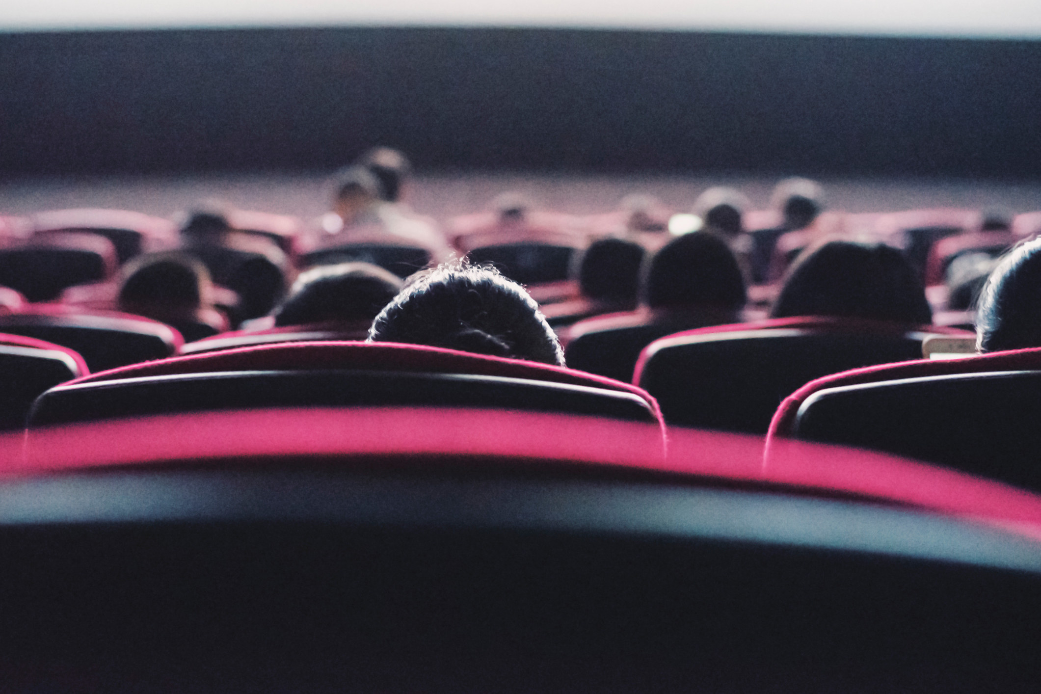 A view of the backs of movie theater seats with people sitting in them