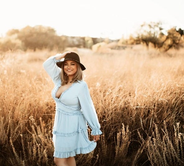 A reviewer wearing the dress in baby blue standing in a field 