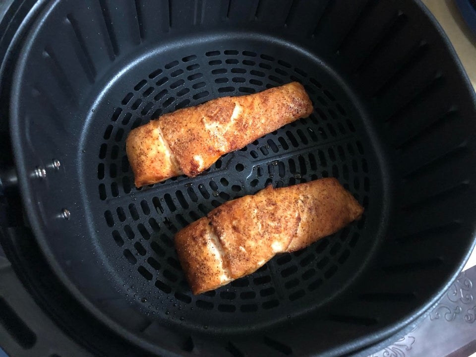 Crispy salmon in the basked of an air fryer.