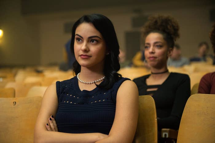 Camila Mendes sits in an auditorium with her arms crossed in Riverdale