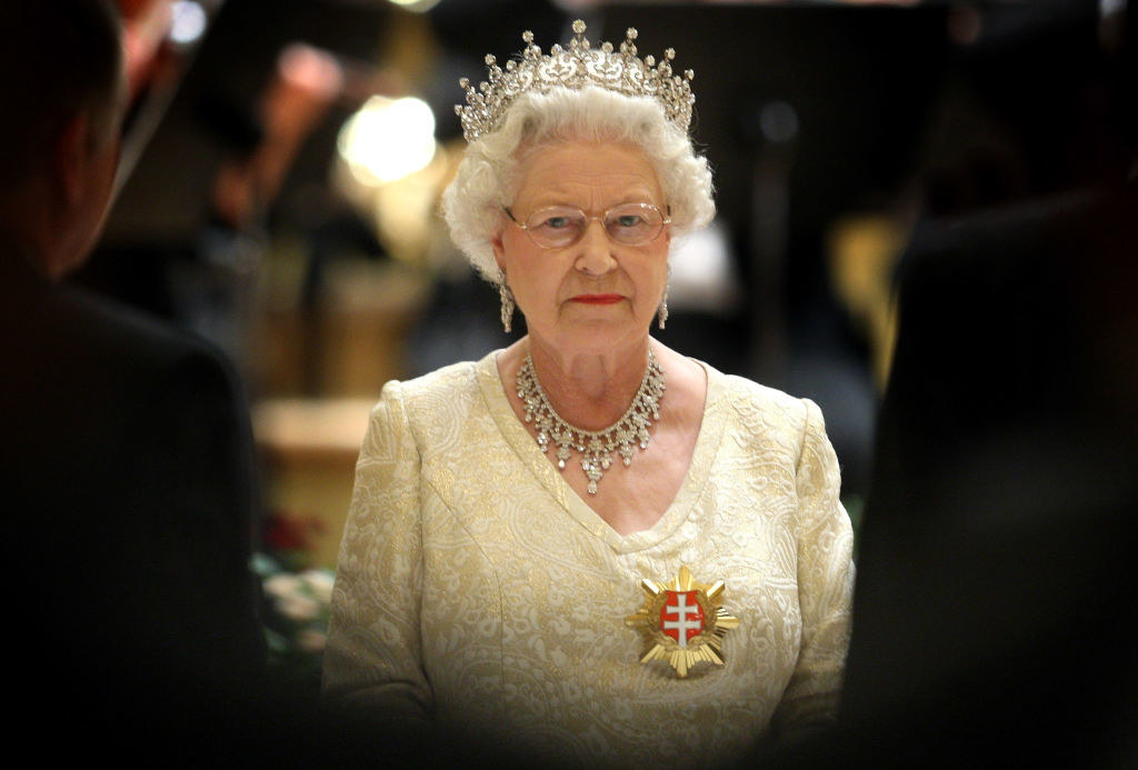 The Queen wearing a crown, matching diamond necklace, and a gown at a formal event