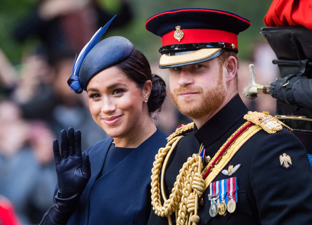 Prince Harry, wearing his military uniform, and Meghan sit in a carriage during a formal event