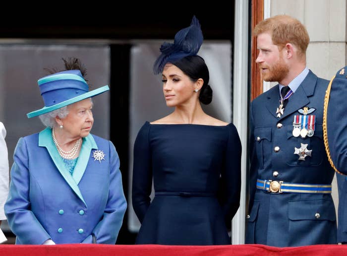 The Queen, Meghan, and Harry standing on a balcony during a events