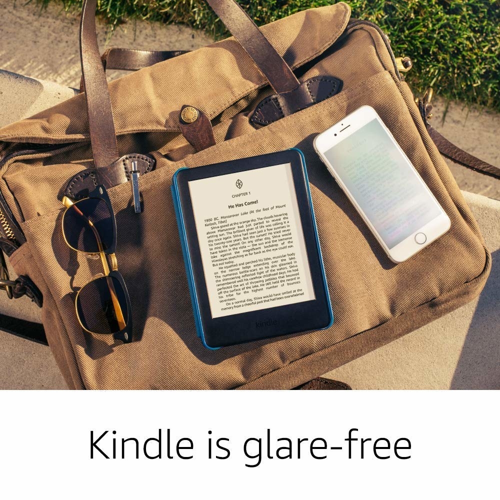 A Kindle on a bag with a pair of sunglasses near it 