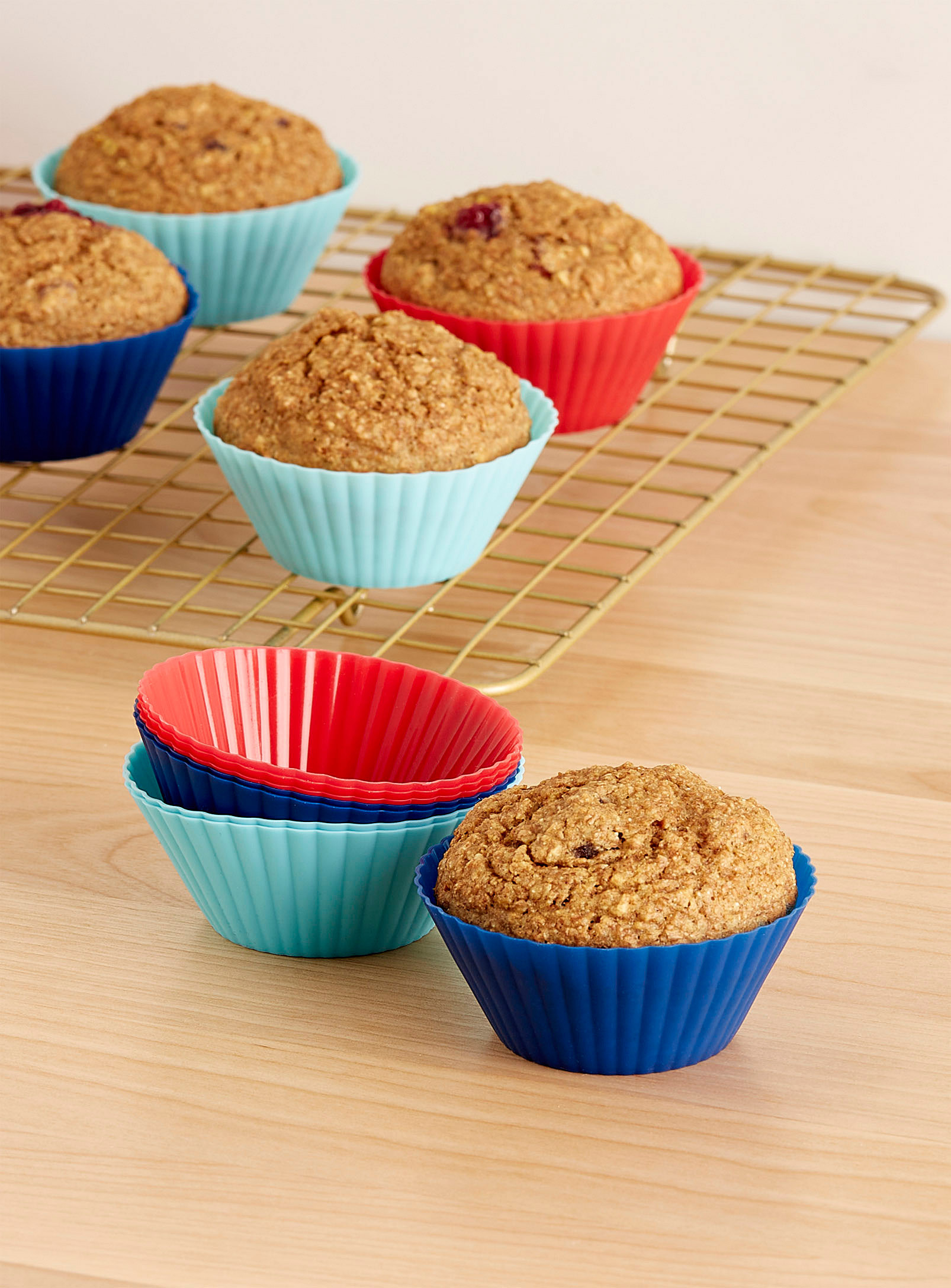 A bunch of muffins in silicone baking cups on a wooden table