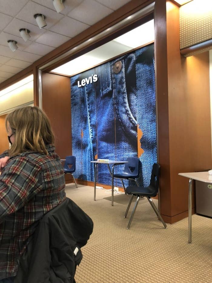 Levi&#x27;s signage remains up behind school desks, a student in the foreground sits wearing a face mask 