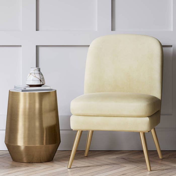 A white slipper-style chair with gold leg