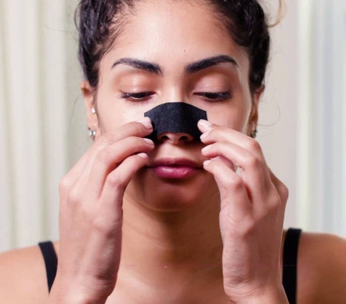 A person removing one of the pore strips from their nose