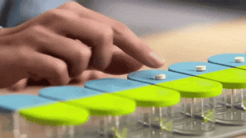 GIF of model pushing pills into the silicone holes of the pill organizer 