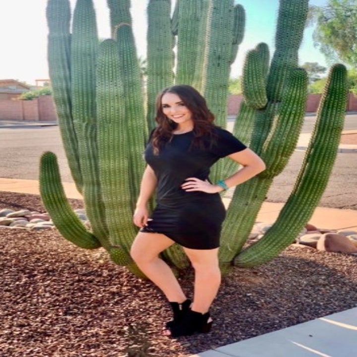 person wearing a black dress while standing in front of a cactus