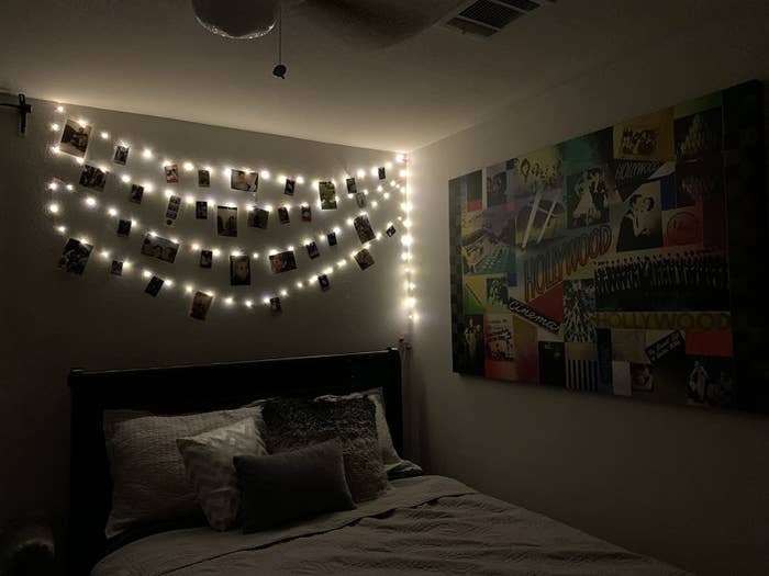 reviewer image of a dark bedroom lit by four long rows of photo clip strings lights hanging on a wall with pictures hanging from each row