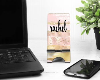 Customized phone stand next to phone and laptop
