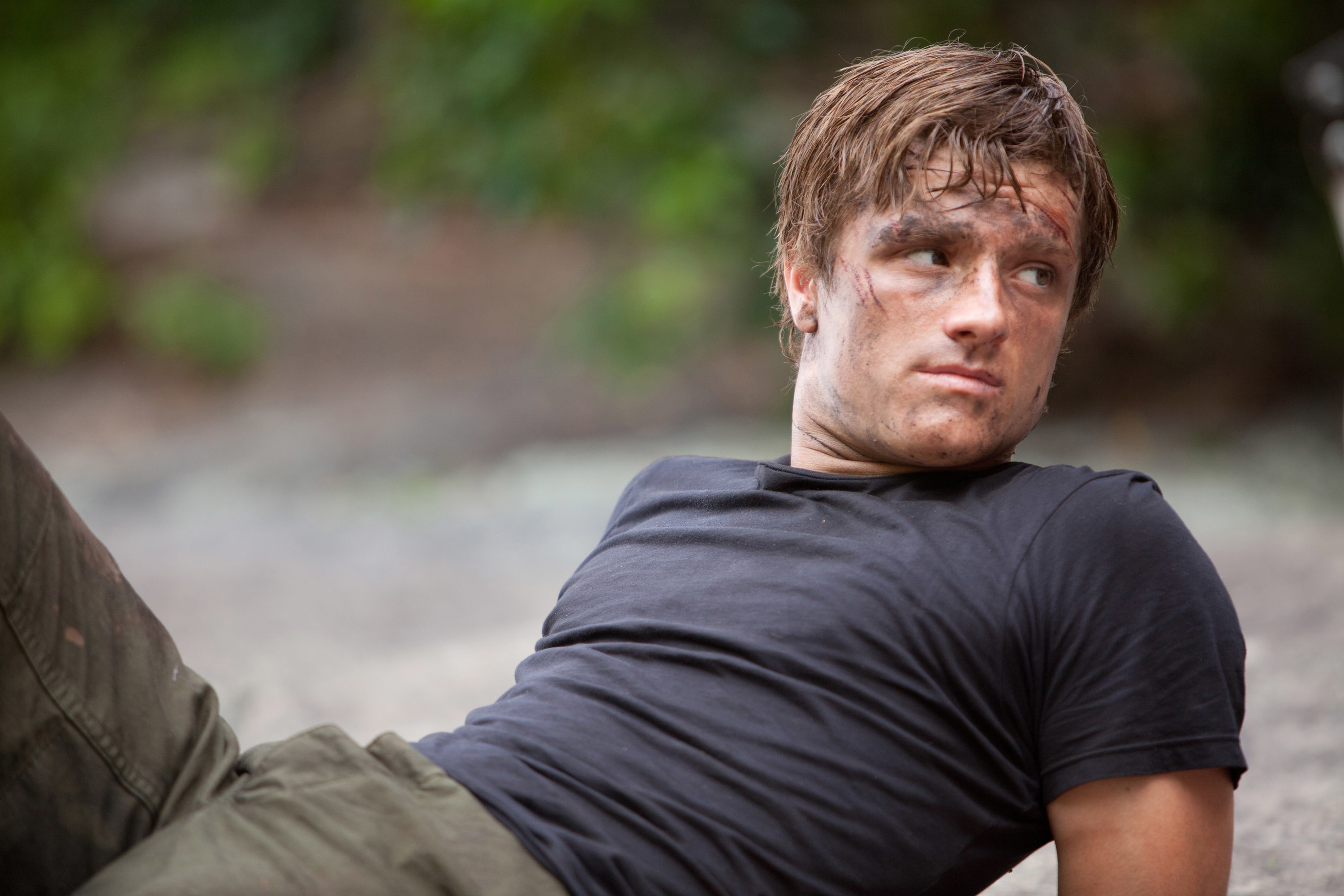 Peeta lying on the ground covered in dirt