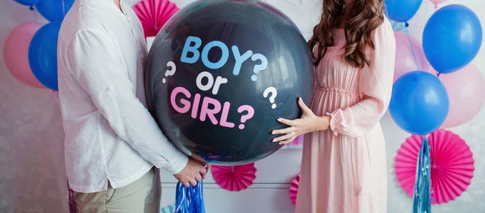 Couple holding a balloon that says "boy or girl?"