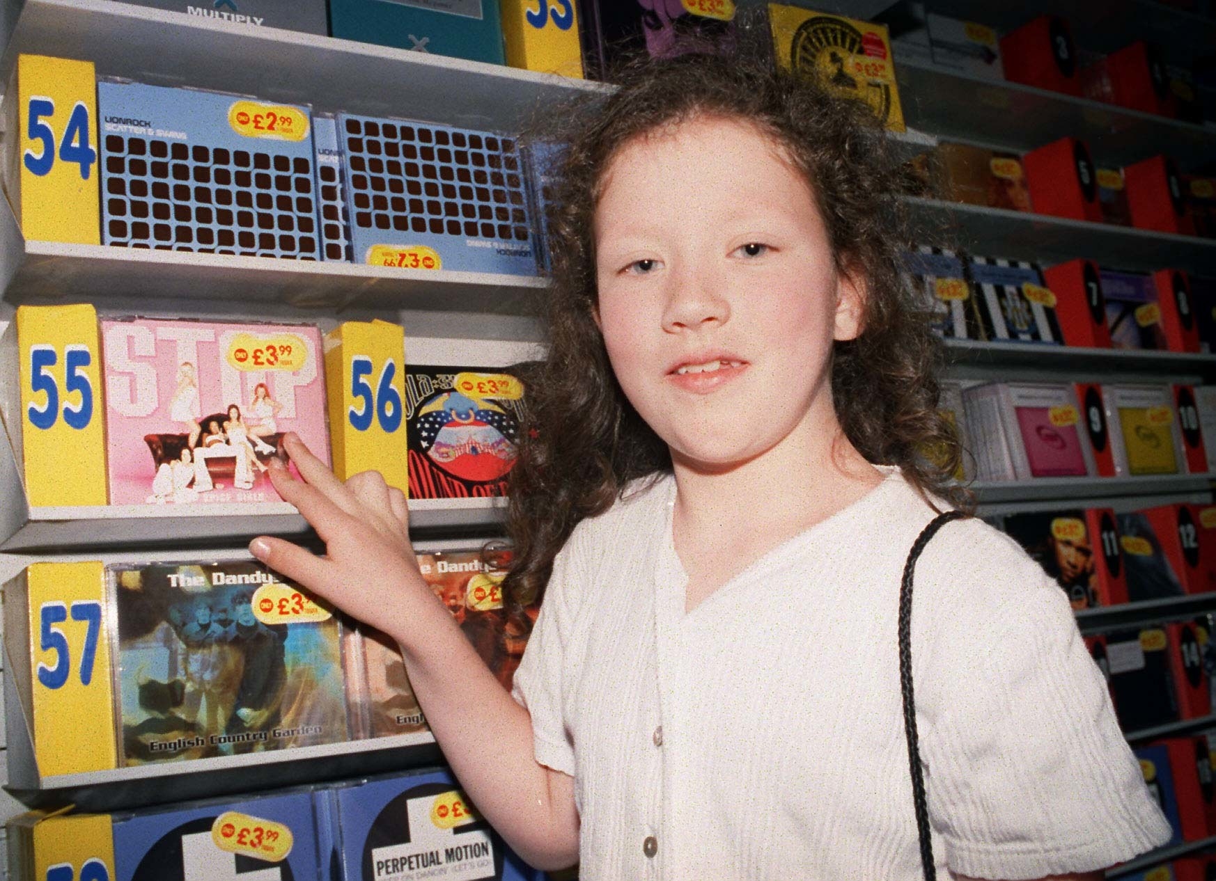 Girl pointing to CDs in a shelf organized in chat order