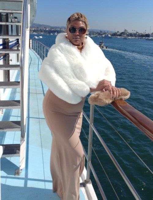 A reviewer wearing the faux fur wrap in white while on a boat