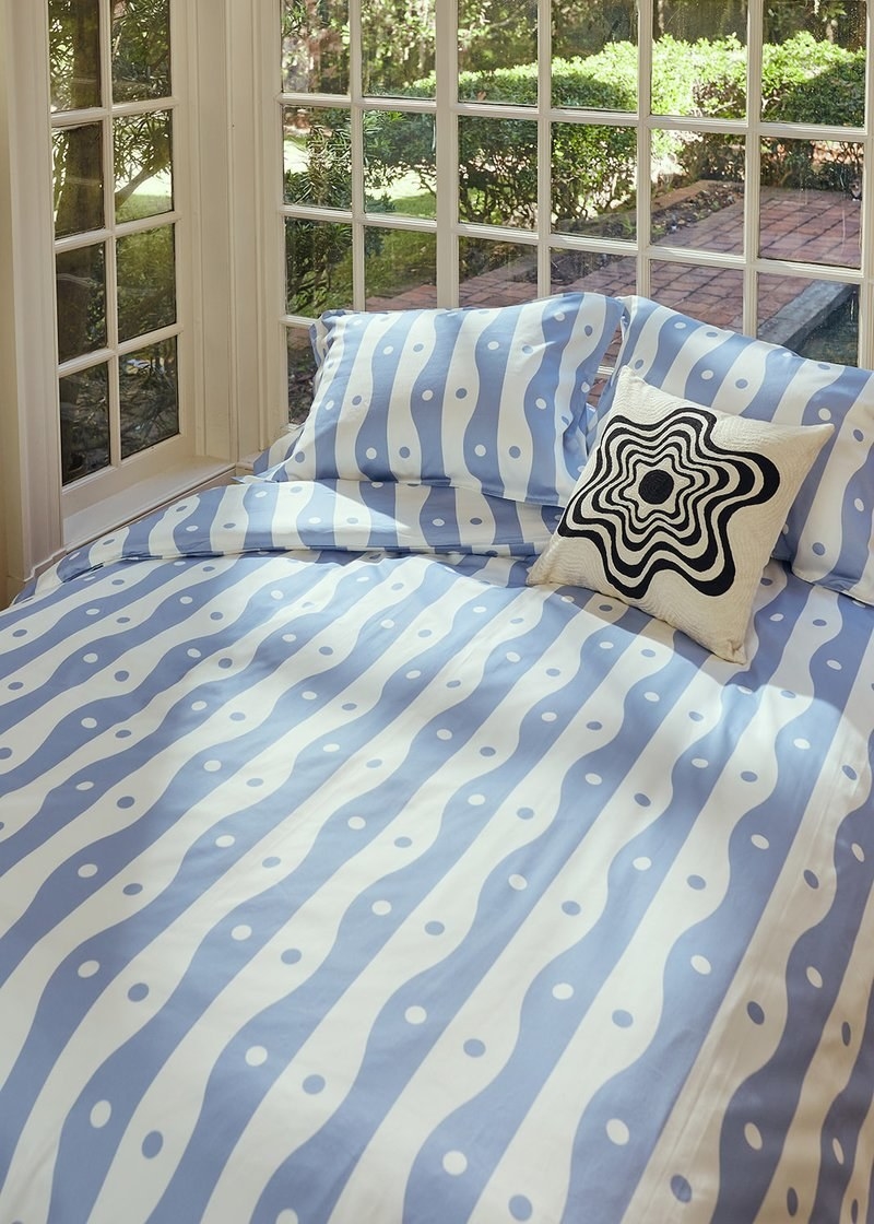 comforter and pillow shams with blue and white squiggly vertical pattern with dots all over it
