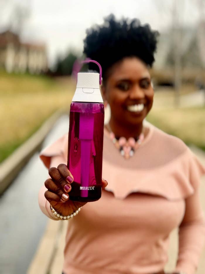 A woman holding up the water bottle
