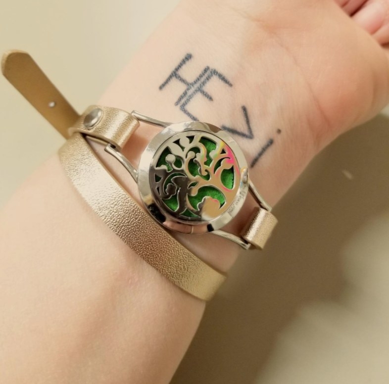 Reviewer wearing the bracelet in green over her tattooed wrist