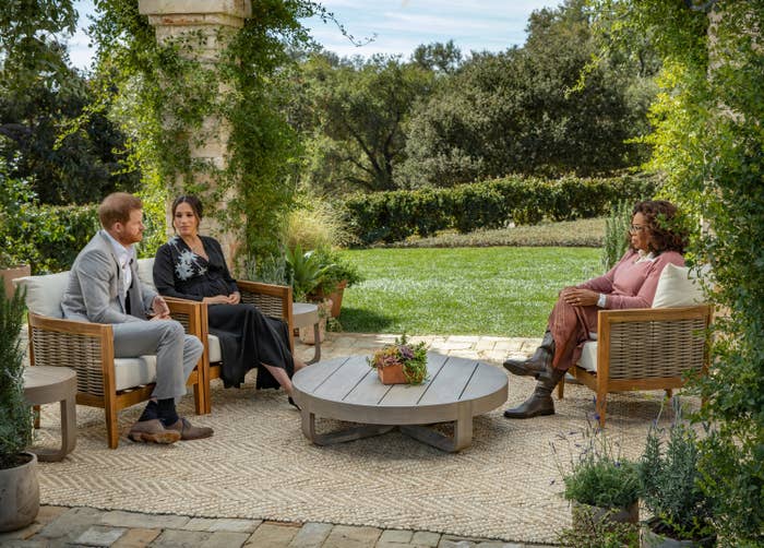 Meghan and Harry look at each other as they are seen sitting across from Oprah