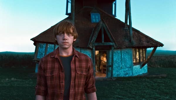 Rupert Grint stands in front of a house in Harry Potter and the Deathly Hollows: Part 1
