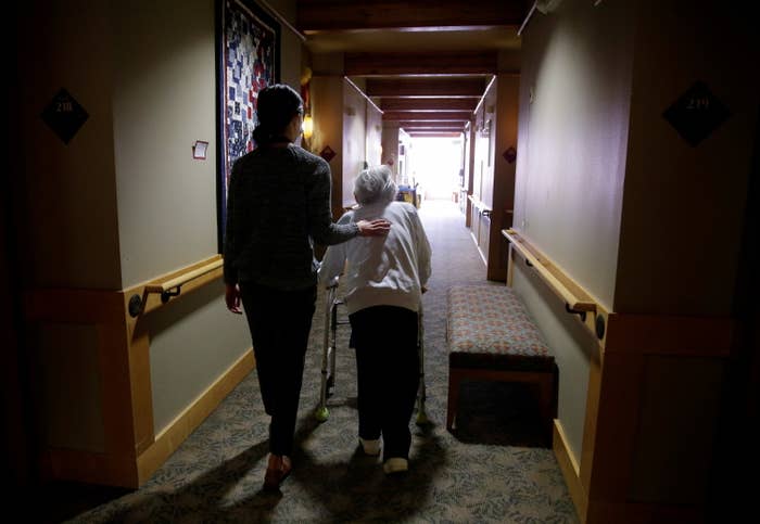 A younger woman and an older woman with a walker go down a hallway