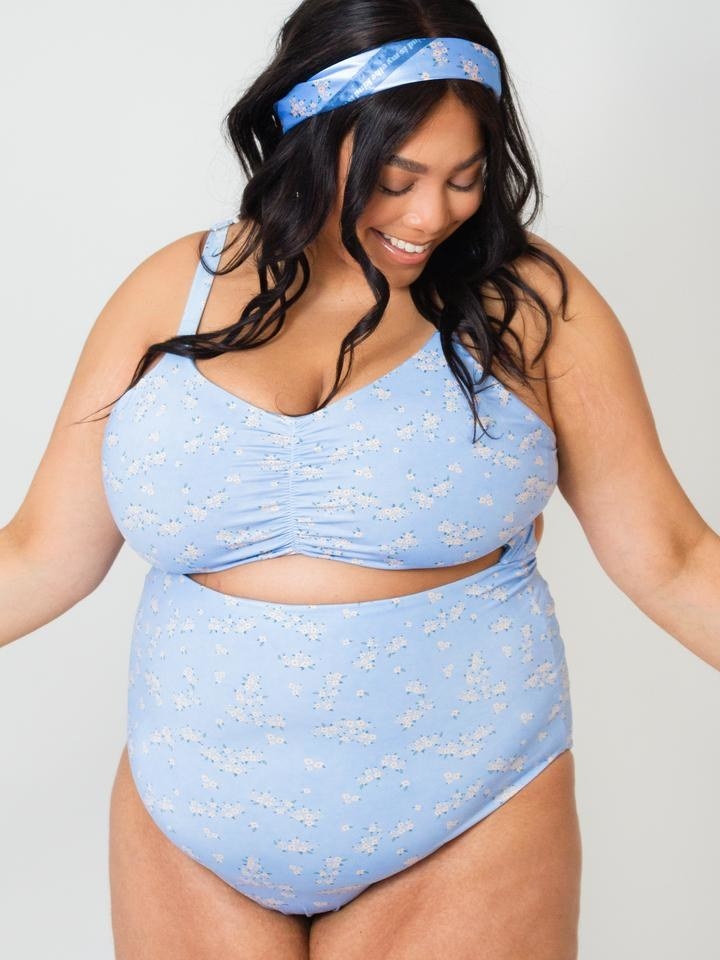 model wearing the one-piece with a cut-out under the bust in light blue with white floral print