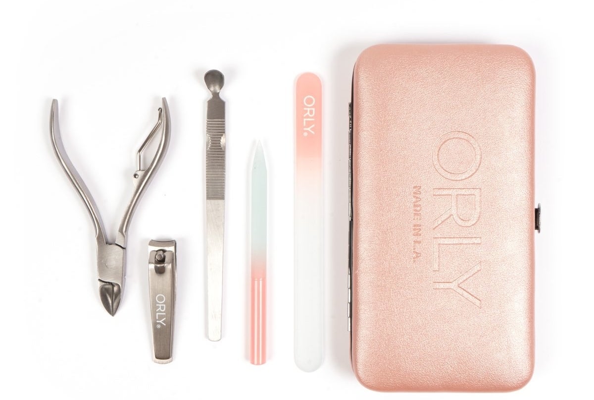 a rose gold-colored case next to nail clippers, flat glass file, rounded glass file, toe nail clippers, and a cuticle pusher
