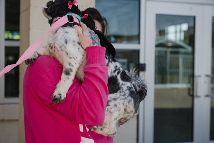 A person holds their small dog to their chest