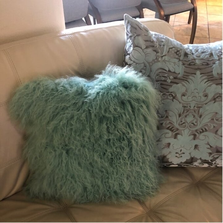 The pillow on a reviewer's couch in mint green 