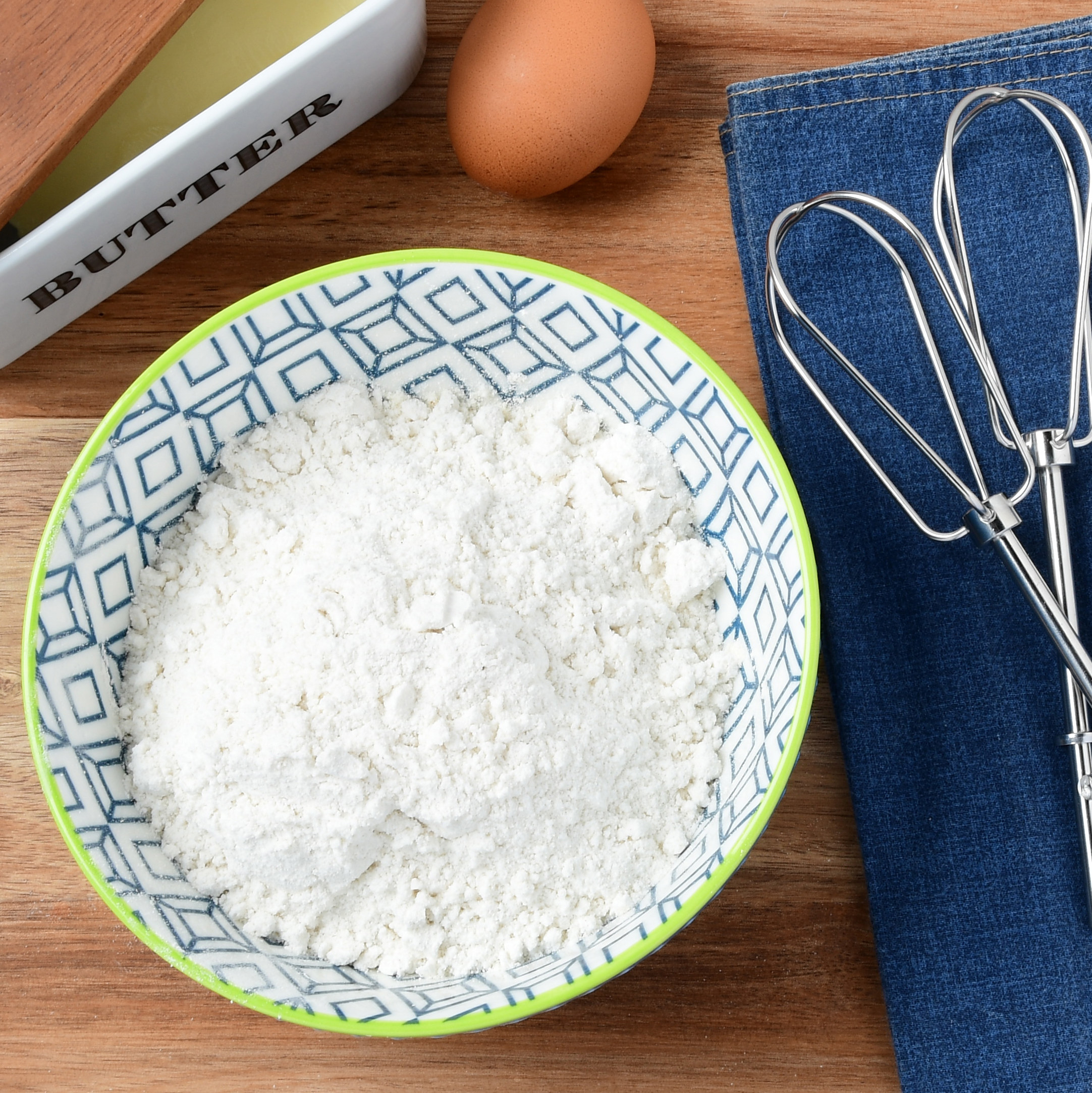 a bowl of flour next to beaters and ingredients