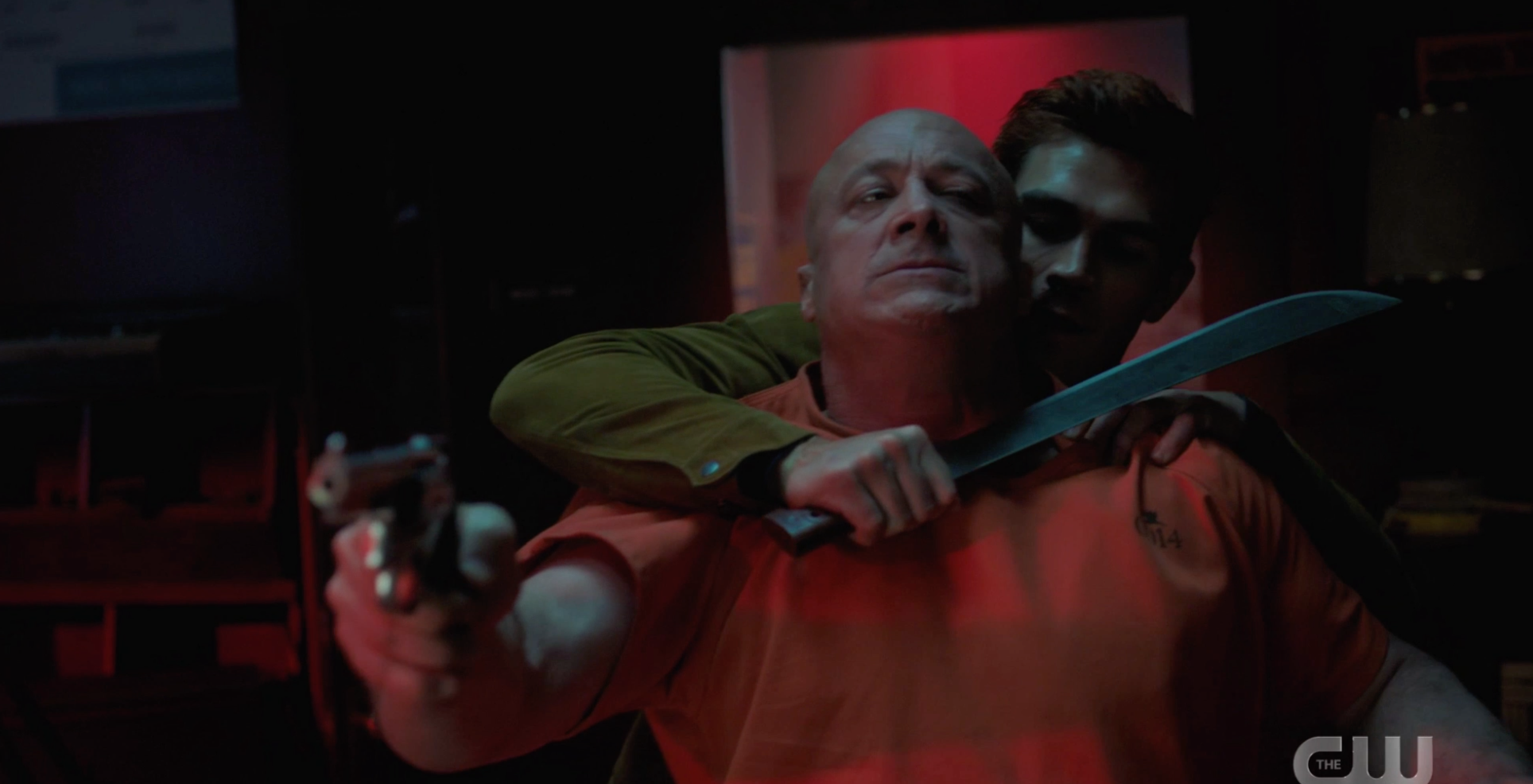 Archie holding a guy at sword point while he aims a gun