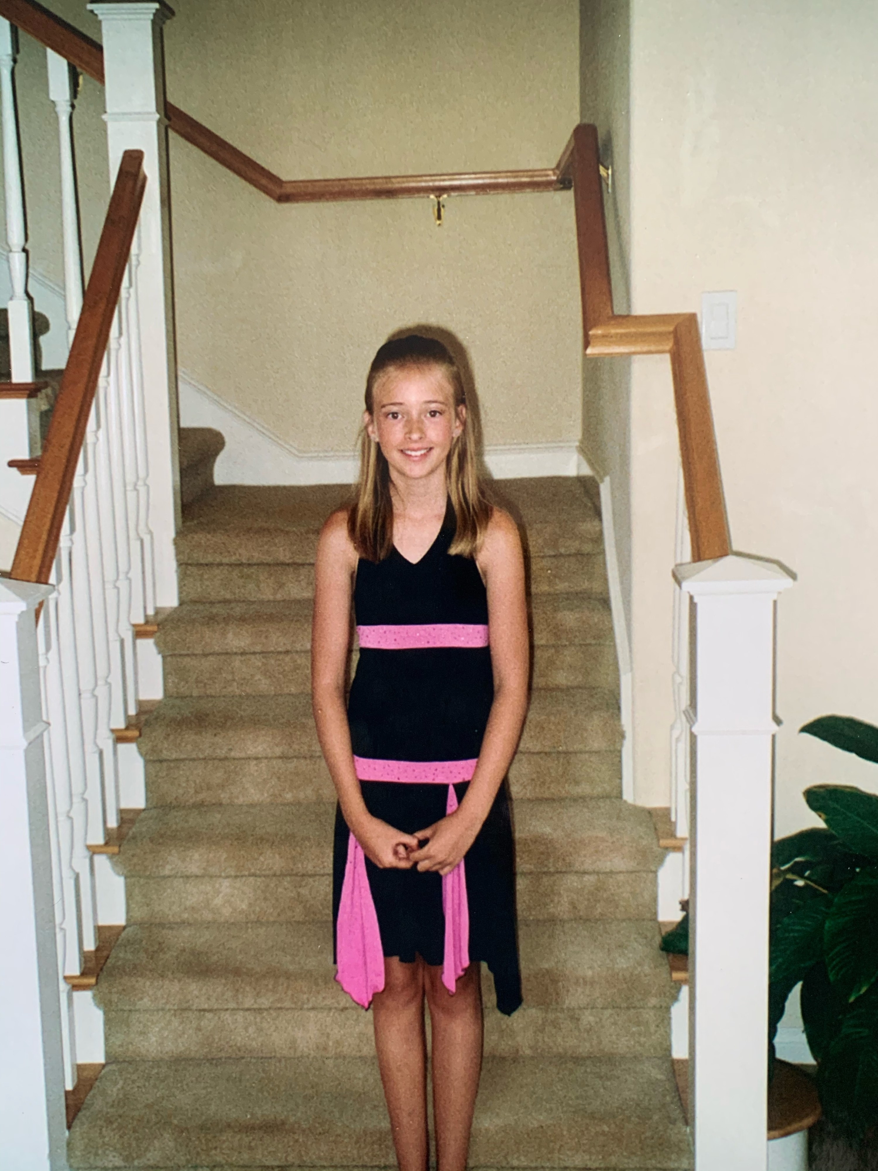 A girl wearing a simple black dress with bright pink embellishments