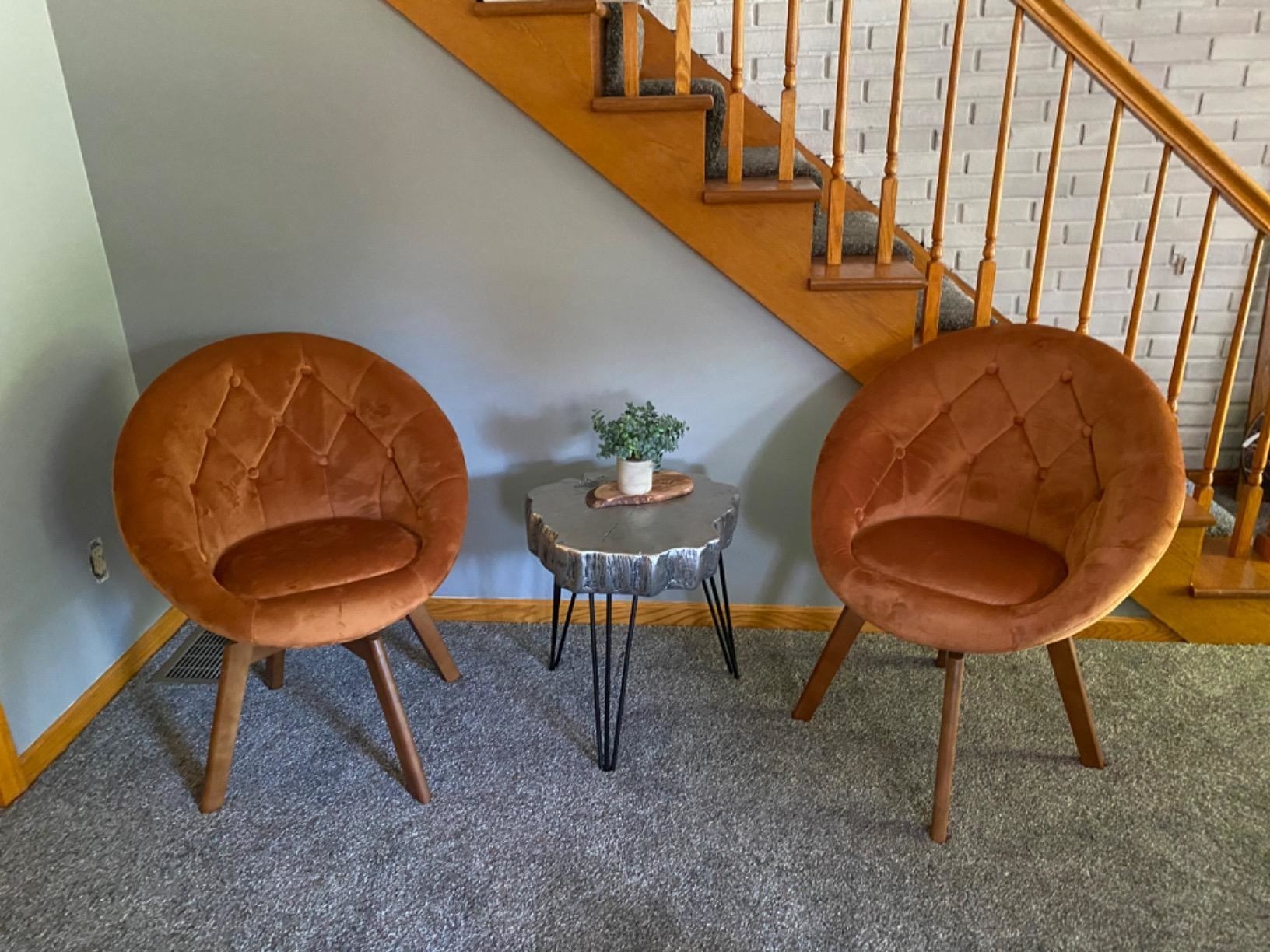 reviewer image of two orange volan Swivel Accent Chairs opposite each other with a small silver table in between
