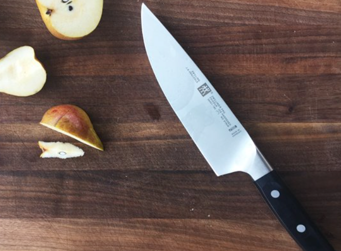 chef&#x27;s knife on cutting board cutting apples