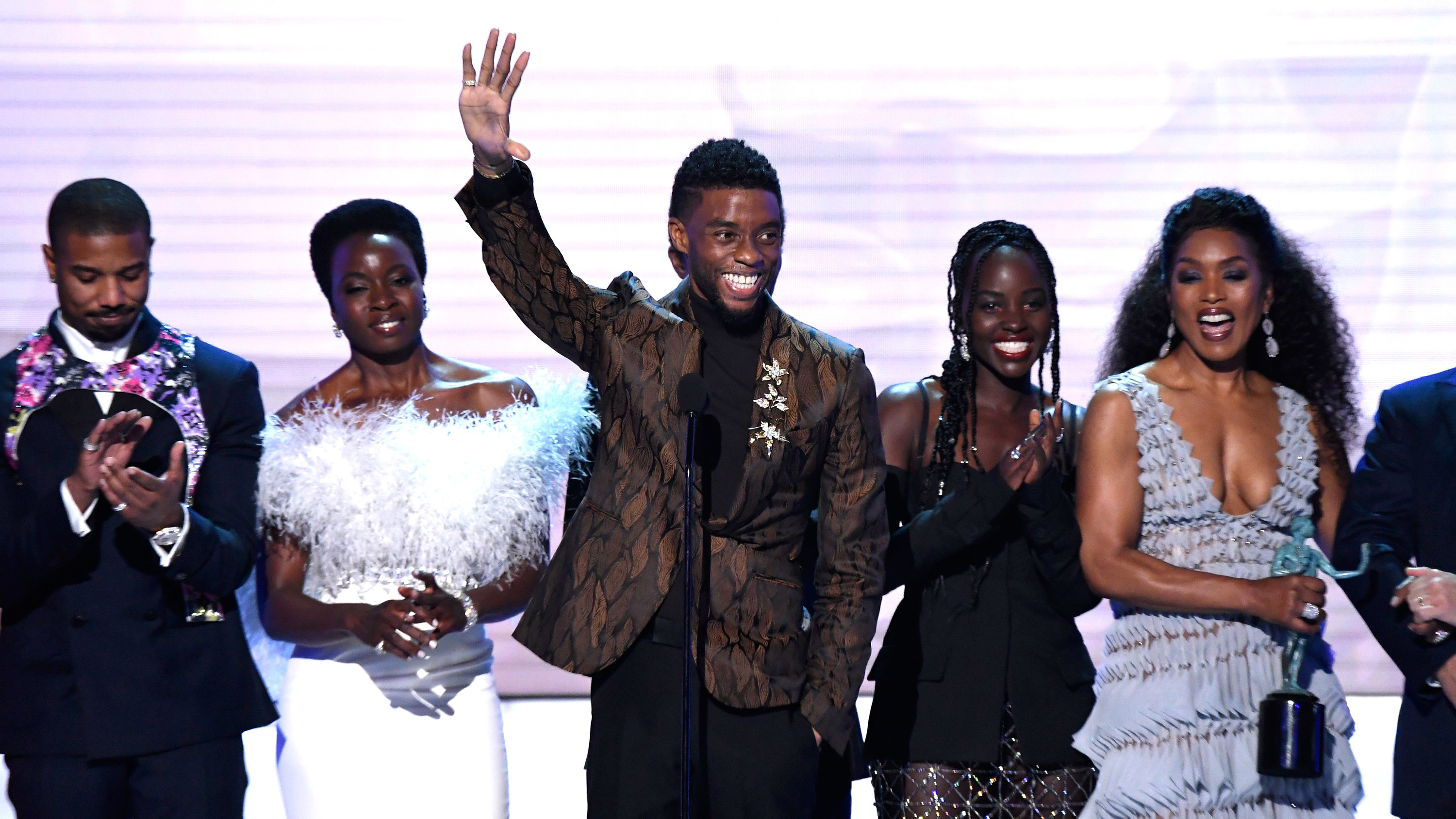 Chadwick waves on stage while surrounded by co-stars