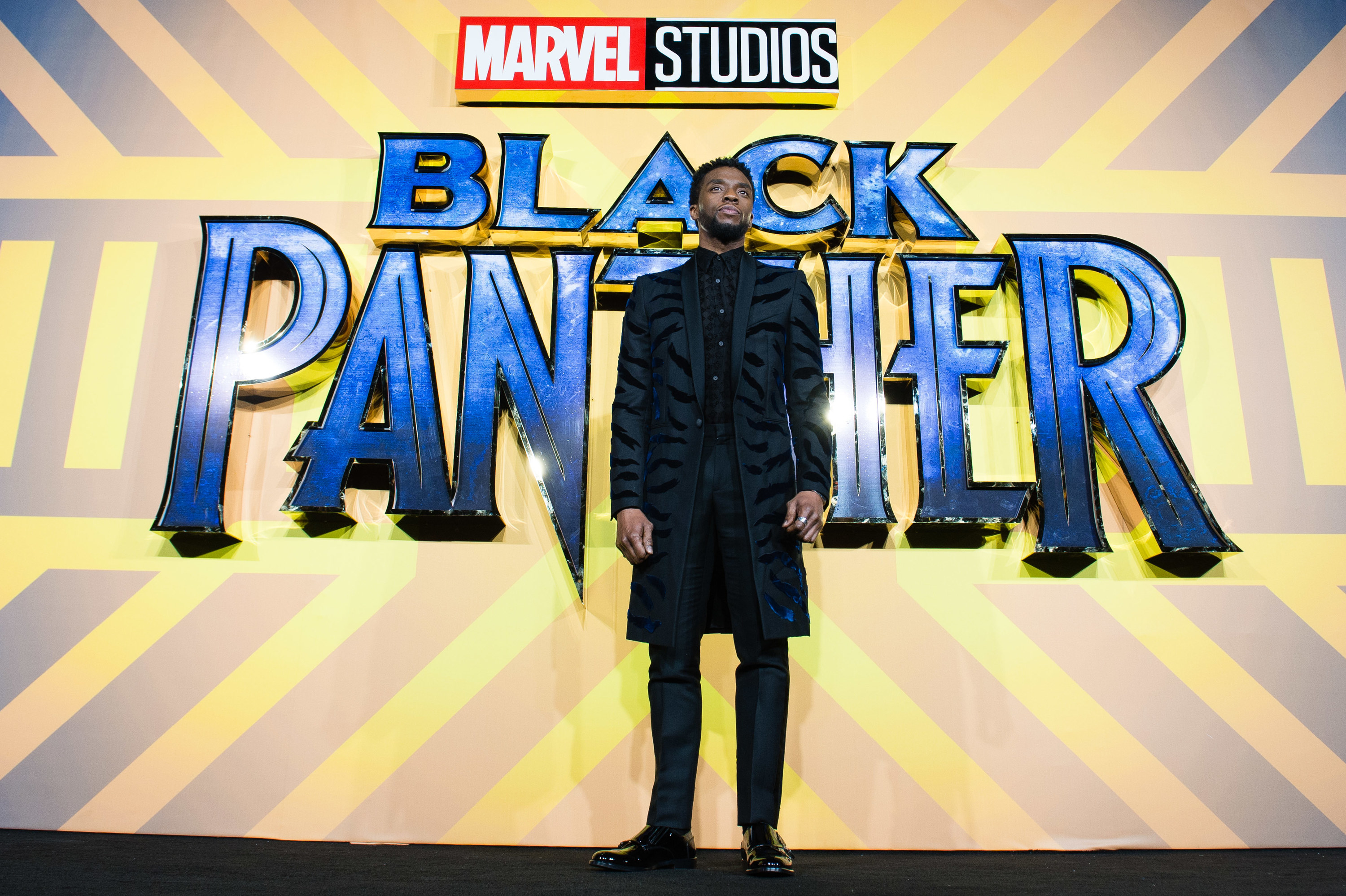 Chadwick stands in front of a large Black Panther poster