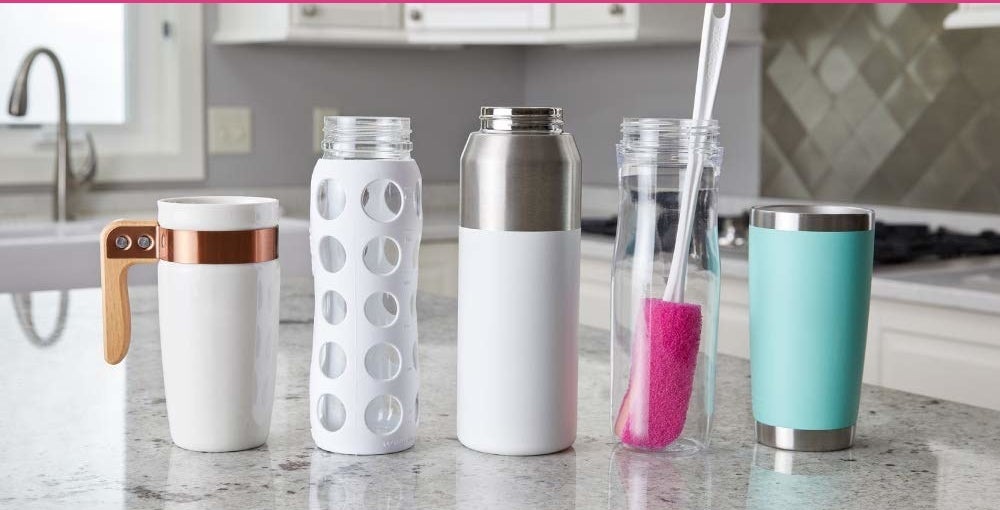 Different types of bottles and the brush kept on a kitchen counter.