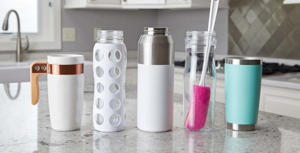 Different types of bottles and the brush kept on a kitchen counter.