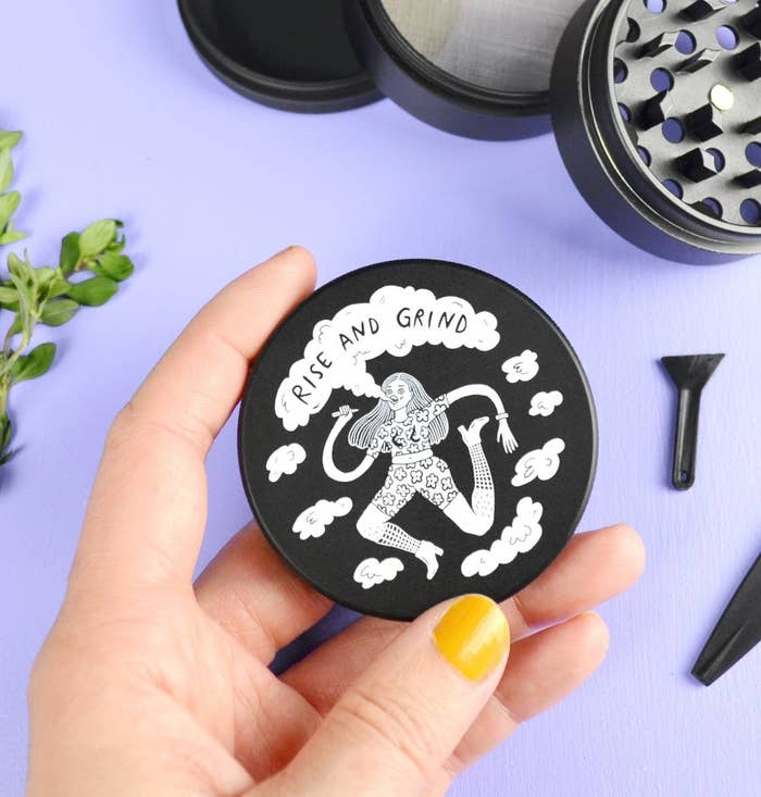 A person holding the top plate of the herb grinder