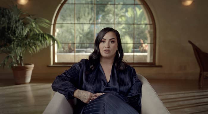 Demi sitting on a couch and discussing what's been going on in her life in the documentary