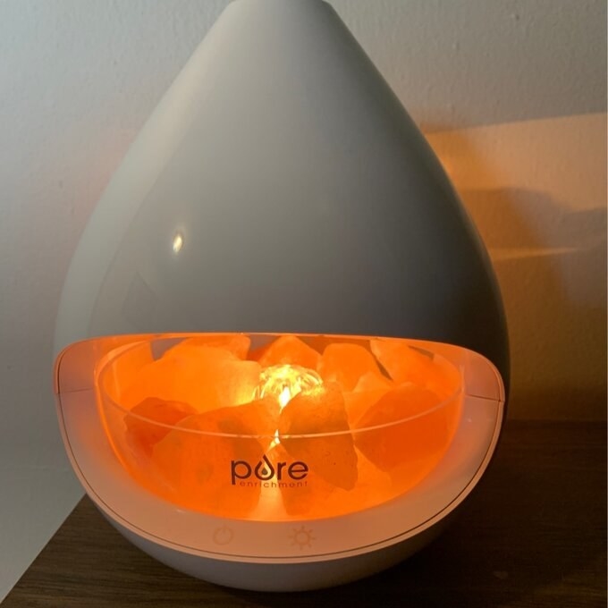 a reviewer&#x27;s crystal oil diffuser which is glowing orange