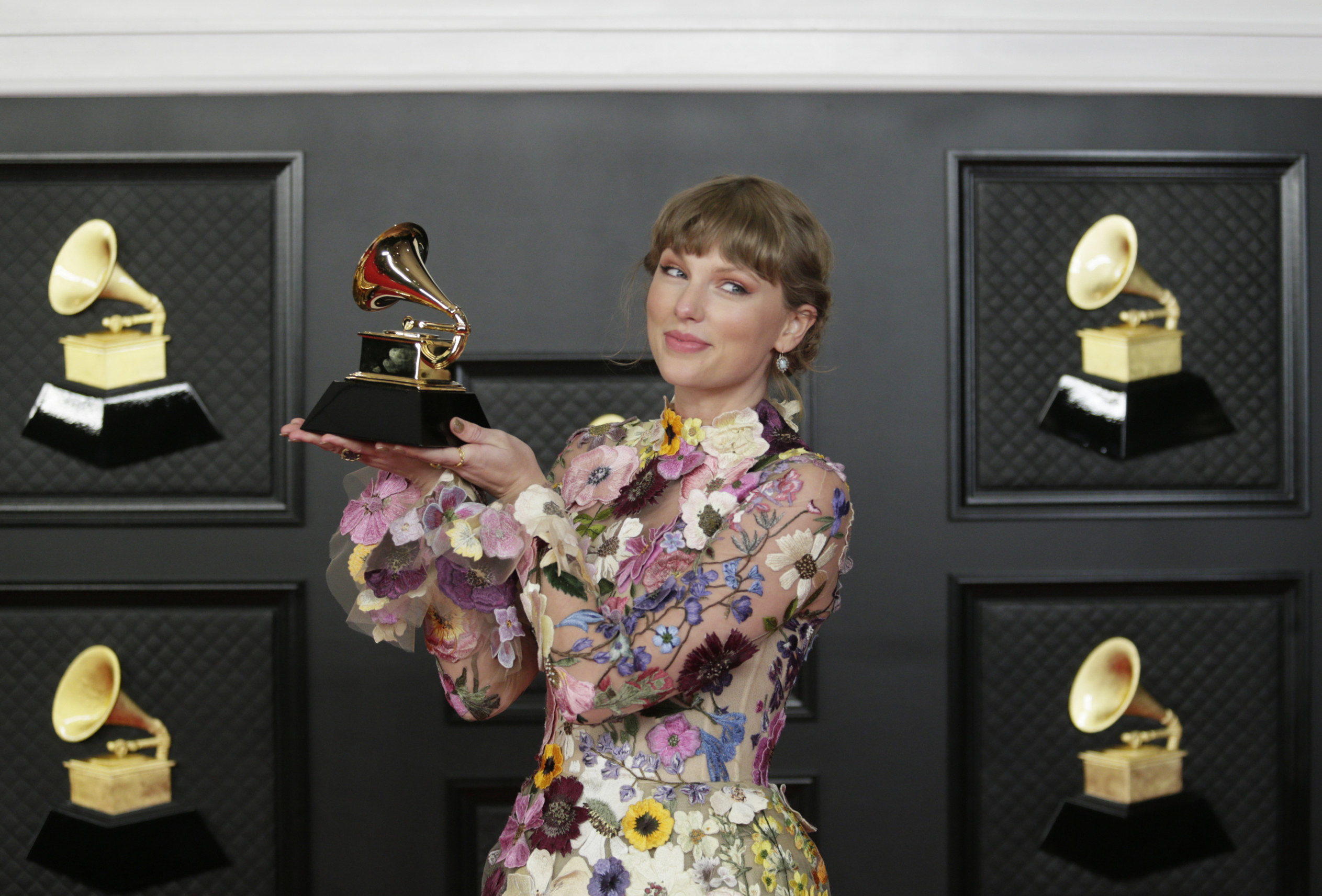 Taylor holding a Grammy on the red carpet